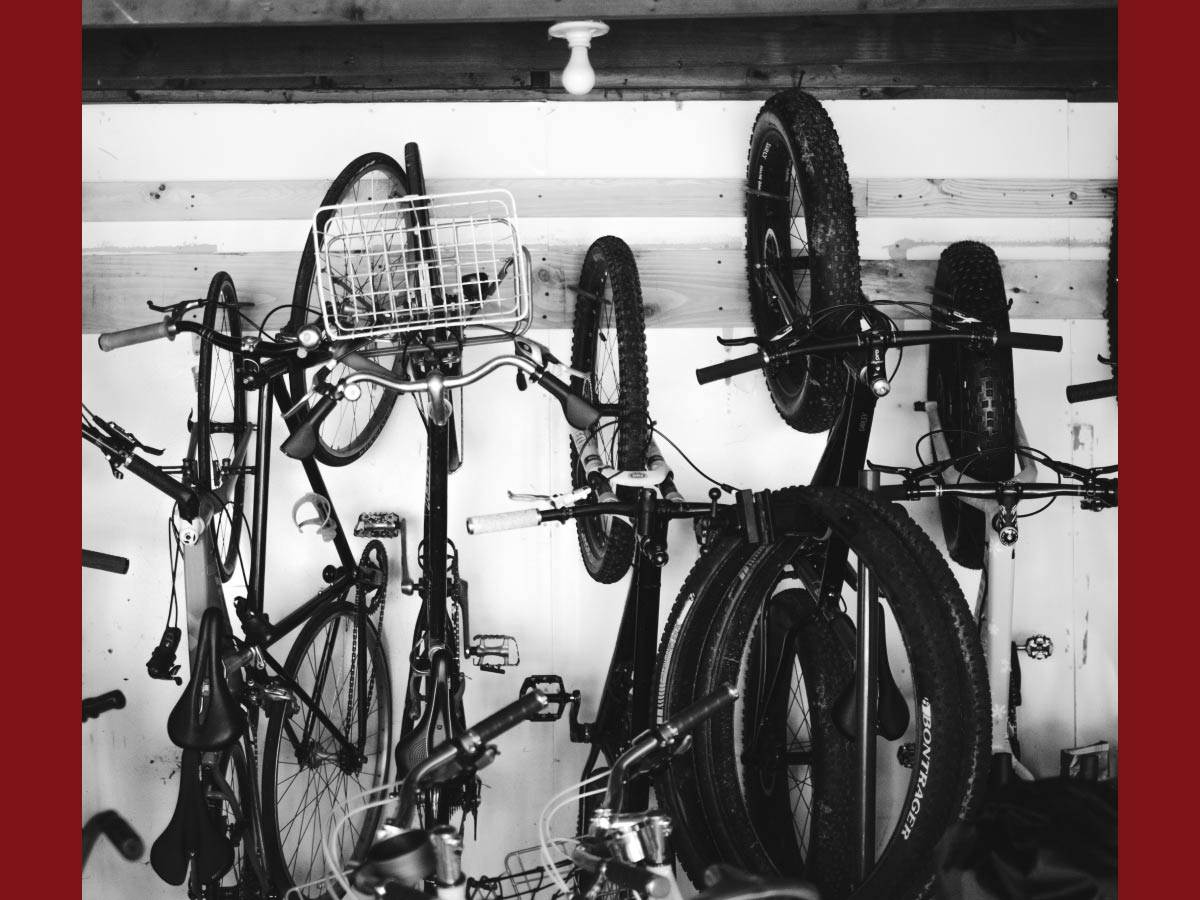 White and black photo of various bikes hanging on wall of barn