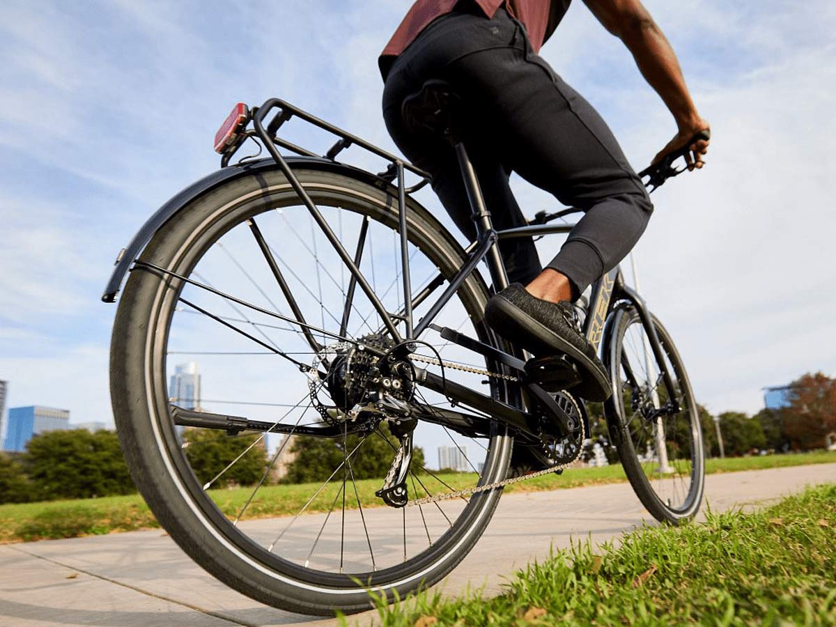 Cyclist riding bike on paved path with trees in background