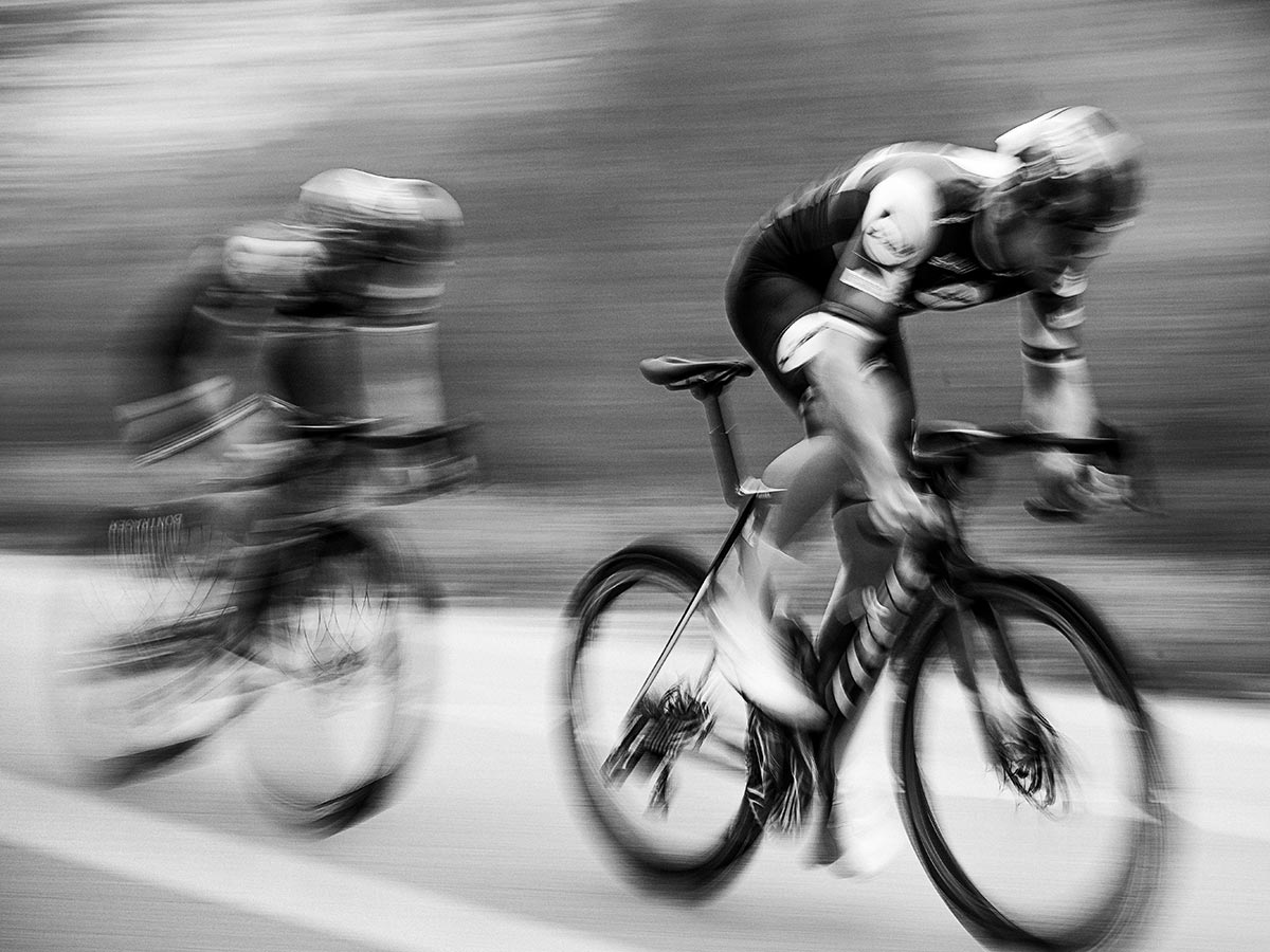 Blurred image of cyclists wearing helmets while racing bicycles