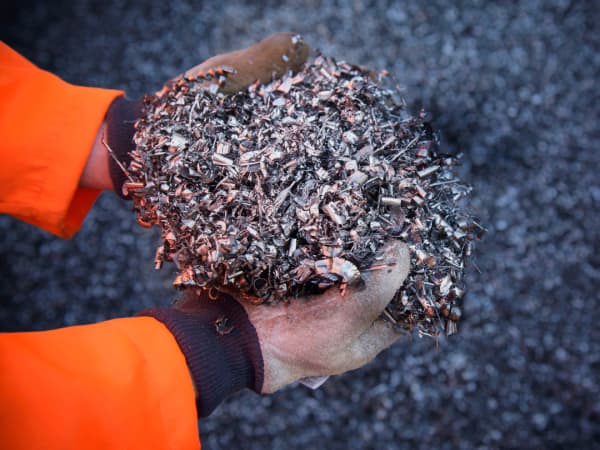 Gloved hands holding a pile of raw aluminum chunks