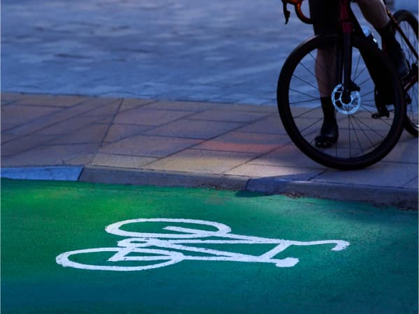 A bicycle in a dimly lit city area up on a curb looking down at a green bicycle lane